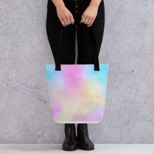 A person holding a pastel-colored tote bag with a soft, cloud-like pattern reminiscent of the aurora borealis, against a grey concrete background, illustrating the bag's practicality and aesthetic appeal.