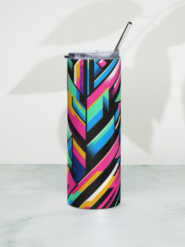 A stainless steel tumbler with a colorful geometric design and a metal straw, positioned on a marble surface with a shadowed background.