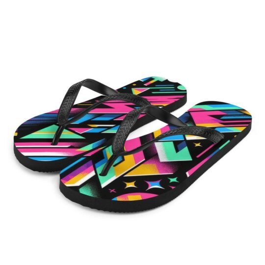 A pair of ZestFiesta Flip-Flops with a vibrant, multicolored geometric design on the insole, resting on a wooden surface beside a straw hat, suggesting a beach or summer setting. The pattern includes shades of pink, blue, yellow, and black.