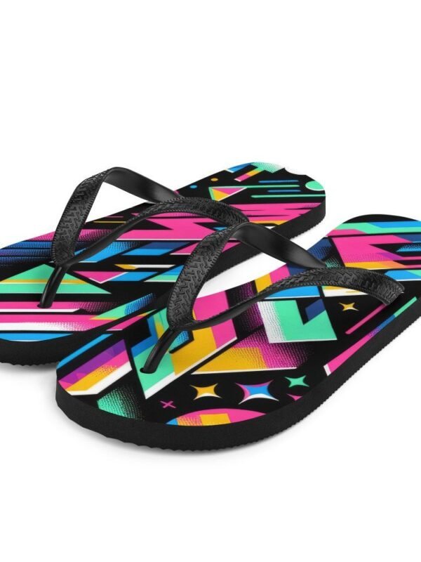 A pair of ZestFiesta Flip-Flops with a vibrant, multicolored geometric design on the insole, resting on a wooden surface beside a straw hat, suggesting a beach or summer setting. The pattern includes shades of pink, blue, yellow, and black.