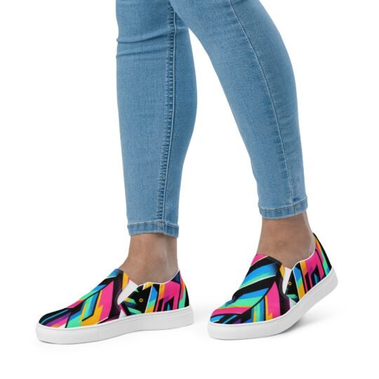 Colorful abstract geometric-patterned slip-on sneakers with a black canvas upper, bright pink, blue, and yellow shapes, elastic side accents for easy wear, and a contrasting white rubber sole for superior comfort and traction.